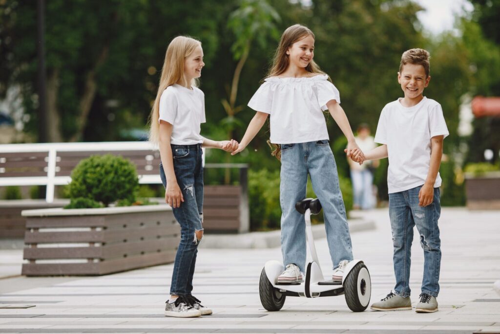 children-learn-ride-hoverboard-park-sunny-summer-day-min